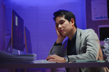 Tired businessman falling asleep while working late at night in office