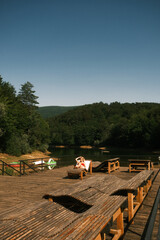 A woman sits comfortably on a dock chair by a scenic lake