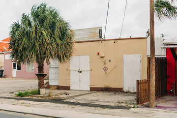Abandoned building in a quiet urban area with palm trees on a cloudy day in late spring