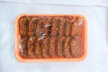 Spicy sausage slices vacuum packed in orange marinade tray awaiting buyers. smoked sausage. packaged product.