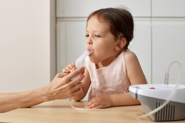 woman makes inhalation to sick toddler child girl at home
