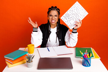 Young female student expressing frustration while studying with geometry homework and book at a...