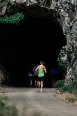 Joggers entering a tunnel in rocky terrain.