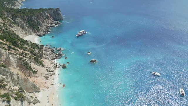 A scenic view of a sandy beach on Ithaki island, Greece. People are swimming and relaxing under the sun while a large cruise ship anchors nearby in the turquoise sea. Perfect summer travel atmosphere.