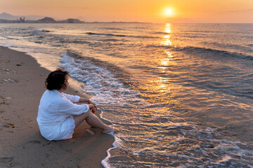 Woman meditating at sunrise on the beach, embracing slow living