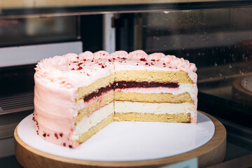 Sliced strawberry cake on display in cafe showcase behind glass.