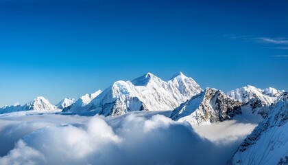 Obraz premium snow covered mountain peaks above clouds under a bright blue sky