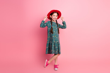 Stylish young girl posing in casual outfit with vibrant pink background, showcasing cheerful energy and trendy childhood fashion
