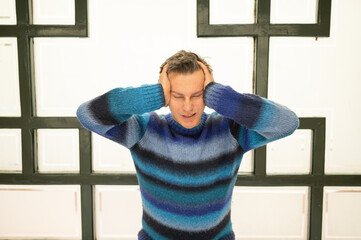 Stressed man suffering from headache and covering ears with hands
