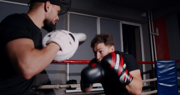 In a dim boxing ring, a determined man showcases his skills in an intense match