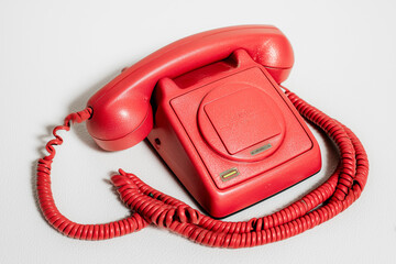 A retro red telephone from an past era, around the 1950s to the 1970s. Taking an urgent phone call.