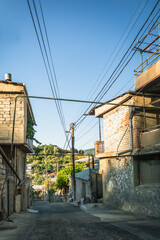 Evening light on a narrow residential street in Tbilisi with stone walls, balconies, and rooftops. The warm tones create a cozy and inviting urban atmosphere.