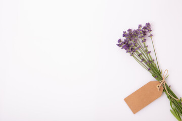 Lavender bouquet with blank kraft tag on white background, minimal composition with copy space, spa branding, natural cosmetics, herbal packaging, wellness promotion, handmade gift design