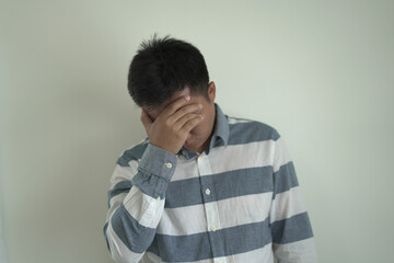 An asian unhappy and annoyed business man is suffering headache and stresses, closing his ears with...