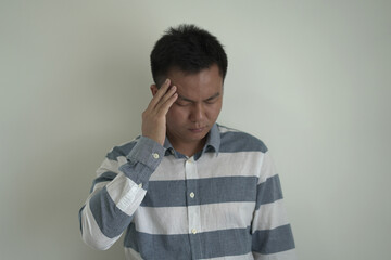 An asian unhappy and annoyed business man is suffering headache and stresses, closing his ears with...