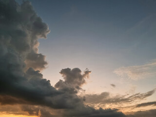 Massive dark clouds towering against a fading sunset sky with warm golden light below