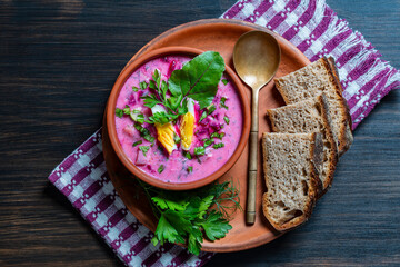 Cold beet soup, traditional Ukrainian food made with beetroot, cucumber, radishes, boiled eggs and sour cream. Delicious cold summer beetroot soup in bowl on table, closeup, top view