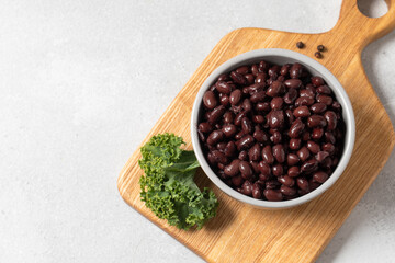Black beans in a bowl on wooden cutting board with kale leaf