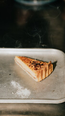 A slice of pie is on a tray with a lot of smoke coming from it. The pie is golden brown and looks delicious