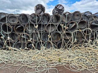 Fishing equipment (cages) stacked on shore in the harbor (basket / crab pot with ropes)