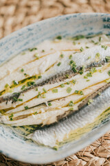 A plate of fish with a green herb garnish. The fish is cut into thin slices and is served in a blue bowl