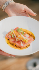 A person is holding a plate with a dish that has a lot of food on it. The plate is white and the food is colorful