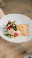 A plate of food with a salad, meat, and bread. The plate is white and the food is colorful