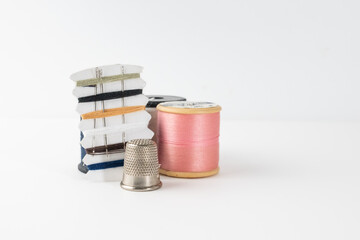 stainless steel protective thimble and a selection of cotton threads and wooden cotton rell