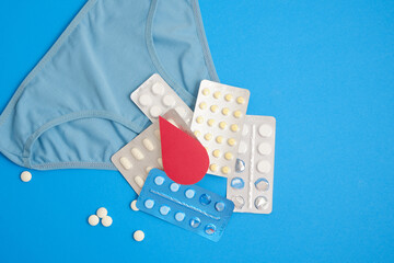 women's comfortable panties small size, blood drop from paper and medical pills, concept of women's health, contraception and PMS first menstruation