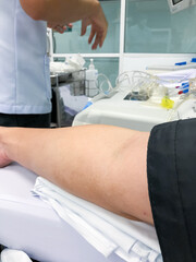 Blood platelet donation, a male nurse inserts a needle into donor’s arm to draw blood at a...