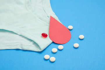 women's comfortable panties small size, blood drop from paper and medical pills, concept of women's health, contraception and PMS first menstruation