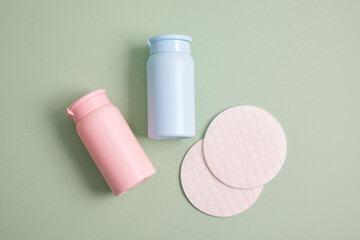 reusable skin care pads and rose and blue mock up cosmetic bottles on green background, pastel...