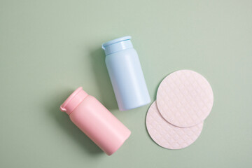 reusable skin care pads and rose and blue mock up cosmetic bottles on green background, pastel shades