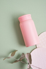 reusable skin care pads and pink mock up cosmetic bottle on green background, pastel shades