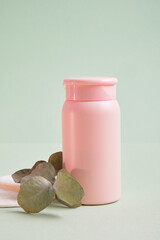 reusable skin care pads and pink mock up cosmetic bottle on green background, pastel shades