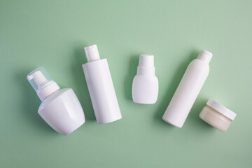 various white bottles of different types on pastel green background top view mock up advertising space