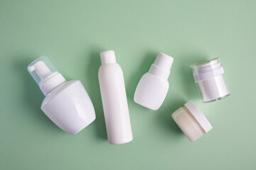 various white bottles of different types on pastel green background top view mock up advertising space