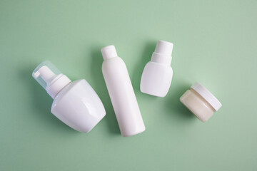 various white bottles of different types on pastel green background top view mock up advertising space