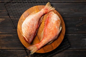 Raw red sea bass or perch on cutting board top view, black seafood food background