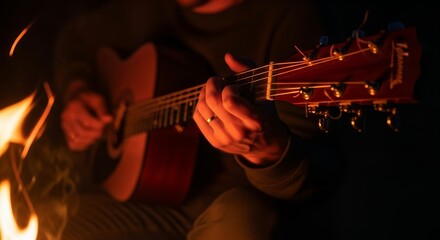 Obraz premium Person enjoying playing beautiful acoustic guitar melodies by the flickering light of a cozy campfire at night tranquil outdoor scene perfect for background music vibes