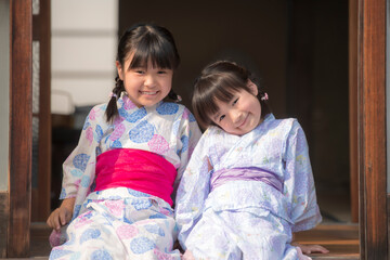 縁側で笑顔を見せる浴衣姿の姉妹
