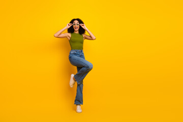 Stylish young woman in casual attire posing against a vibrant yellow background with a cheerful...