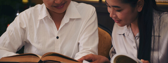Two of Diversity Student study and reading book together in library at asian college. Happy multi ethnic woman search for knowledge in classroom at university. Education concept-banner image.