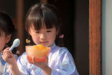 縁側でかき氷を食べる浴衣姿の姉妹