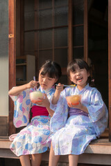 縁側でかき氷を食べる浴衣姿の姉妹
