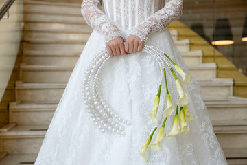 The bride in a white wedding dress holds a bouquet of white flowers - callas.. Wedding. Bride and...
