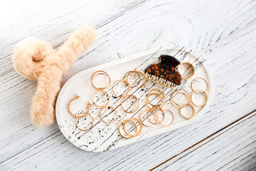 Colorful jewelry arrangement on a decorative tray with a plush accessory in a cozy setting