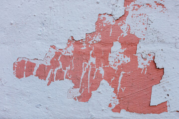 Peeling paint reveals texture and colors on a weathered wall in an urban setting