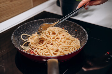 Step by step the process of cooking Italian pasta carbonara in spaghetti, add sauce with fried cubes of pancetta or bacon, eggs, cheese and garnish with basil