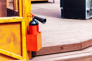 Fire extinguisher mounted on wooden structure near outdoor seating area